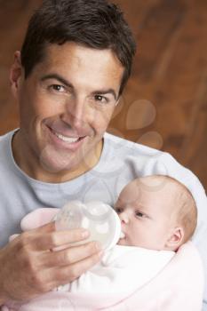 Portrait Of Father Feeding Newborn Baby At Home