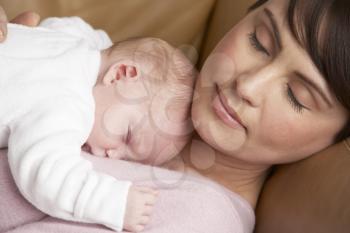 Portrait Of Mother Resting With Newborn Baby At Home