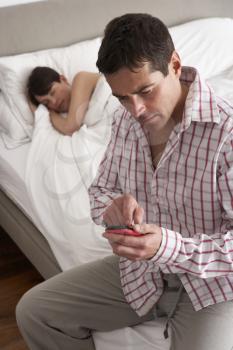 Suspicious Husband Checking Wife's Mobile Phone Whilst She Sleeps