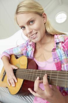 Teenage girl playing acoustic guitar