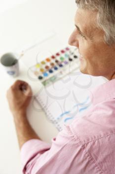 Mid age man painting with watercolors