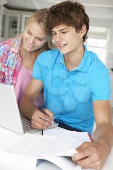 Teenage boy and girl doing homework with laptop