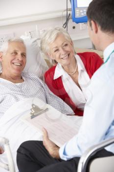 Doctor talking to senior couple on UK Hospital ward