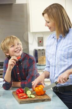 Mother and son preparing food in domestic kitchen