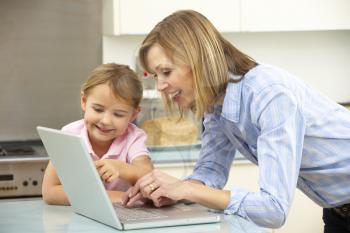 Mother and daughter using laptop in domestic kitchen