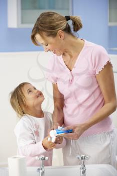 Mother and daughter cleaning teeth in bathroom