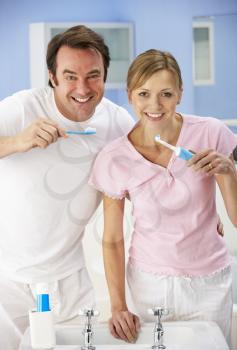 Couple cleaning teeth together in bathroom