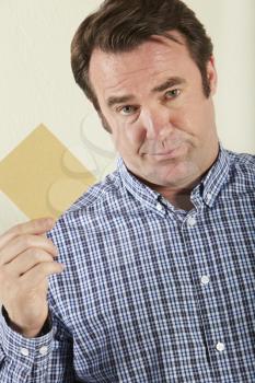 Studio Shot Of Middle Aged Man Holding Wage Packet