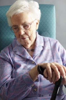 Unhappy Senior Woman Sitting In Chair Holding Walking Stick