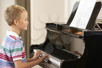 Young boy playing grand piano at home