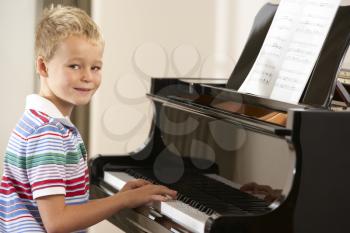 Young boy playing grand piano at home