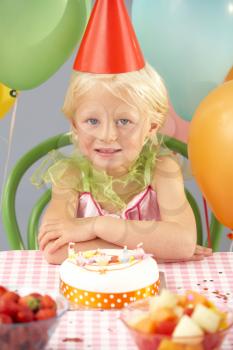 Young girl with birthday cake at party