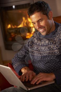 Middle Aged Man Using Laptop Computer By Cosy Log Fire