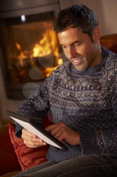 Middle Aged Man Using Tablet Computer By Cosy Log Fire