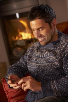 Middle Aged Man Using MP3 Player By Cosy Log Fire