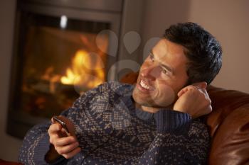 Middle Aged Man Using MP3 Player By Cosy Log Fire