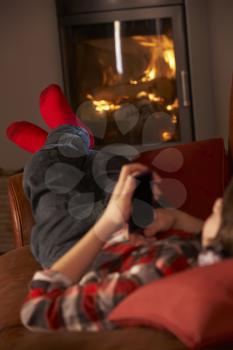 Young Boy Relaxing With MP3 Player By Cosy Log Fire
