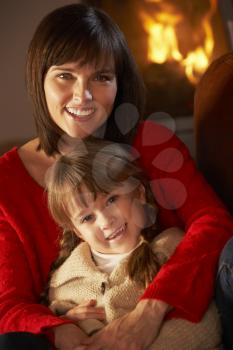 Mother And Daughter Relaxing On Sofa By Cosy Log Fire