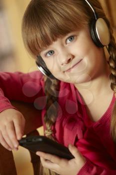 Young Girl Sitting On Wooden Seat Listening To MP3 Player