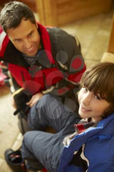 Father Helping Son To Put On Warm Outdoor Clothes And Boots