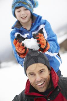 Young Boy About To Drop Snowball On Fathers Head
