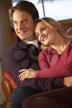 Middle Aged Couple Chatting On Sofa In Chalet With Winter View