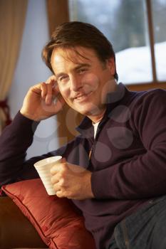 Middle Aged Man Relaxing With Hot Drink On Sofa