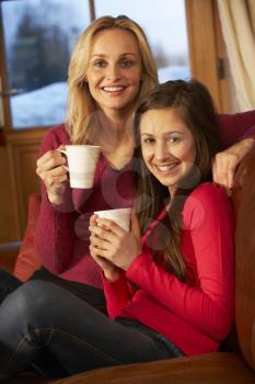 Portrait Of Mother And Daughter Relaxing On Sofa Together With Hot Drink