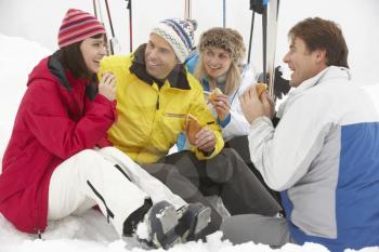 Group Of Middle Aged Friends Eating Sandwich On Ski Holiday In Mountains