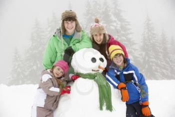 Group Of Children Building Snowman On Ski Holiday In Mountains