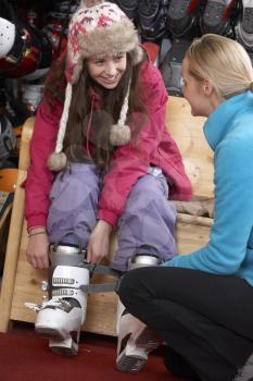 Sales Assistant Helping Teenage Girl To Try On Ski Boots In Hire Shop
