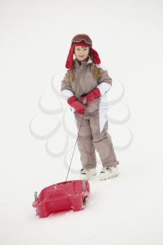 Young Girl Pulling Sledge On Ski Holiday In Mountains