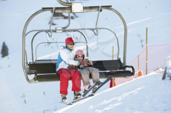 Mother And Daughter Getting Off chair Lift On Ski Holiday In Mountains