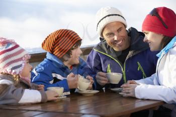 Family Enjoying Hot Drink In Caf At Ski Resort