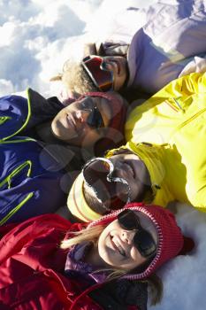 Overhead View Of Teenage Family Lying In Snow On Ski Holiday In Mountains