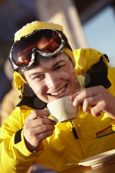 Teenage Boy Enjoying Hot Drink In Caf At Ski Resort