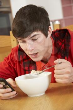 Teenage Boy Teenage Texting Whilst Eating Breakfast