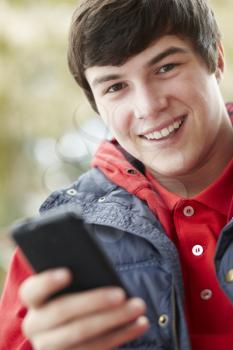 Teenage Boy Texting On Smartphone Wearing Winter Clothes