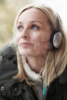 Woman Wearing Headphones And Listening To Music Wearing Winter Clothes