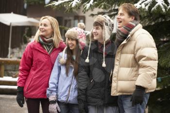 Teenage Family Walking Along Snowy Town Street In Ski Resort
