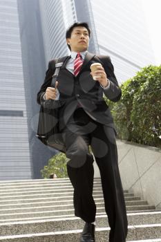 Chinese Businessman Rushing Down Steps Carrying Bag And Takeaway Coffee