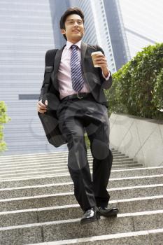 Chinese Businessman Rushing Down Steps Carrying Bag And Takeaway Coffee