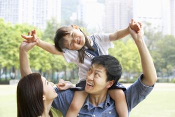 Chinese Family Giving Daughter Ride On Shoulders In Park