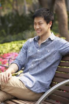 Young Chinese Man Relaxing On Park Bench