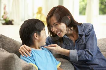 Chinese Mother And Son Sitting On Sofa At Home Together