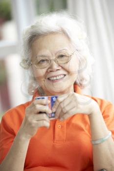 Senior Chinese Woman Drinking Tea On Sofa At Home