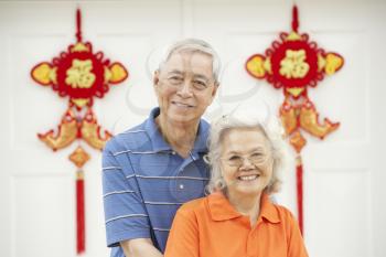 Senior Chinese Couple Outside Home Decorated With Welcoming Feng Shui Banners