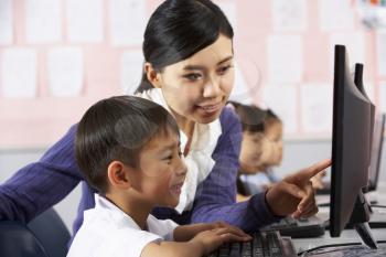 Teacher Helping Student During Computer Class In Chinese School Classroom