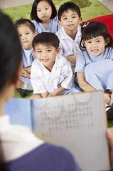 Teacher Reading To Students In Chinese School Classroom