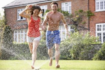 Couple Running Through Garden Sprinkler